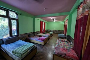 A room with two beds, a sofa, a small table, and a ceiling fan. - Dream Valley Kasol (Kasol)