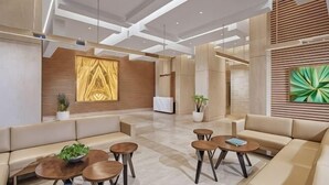 A modern lobby with a reception desk, seating areas, and artwork on the walls. - 3BR Podomoro Apartment @Empire Tower 107 sqm² (Kesawan)