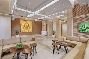 A modern lobby with a reception desk, seating areas, and artwork on the walls. - 3BR Podomoro Apartment @Empire Tower 107 sqm² (Kesawan)