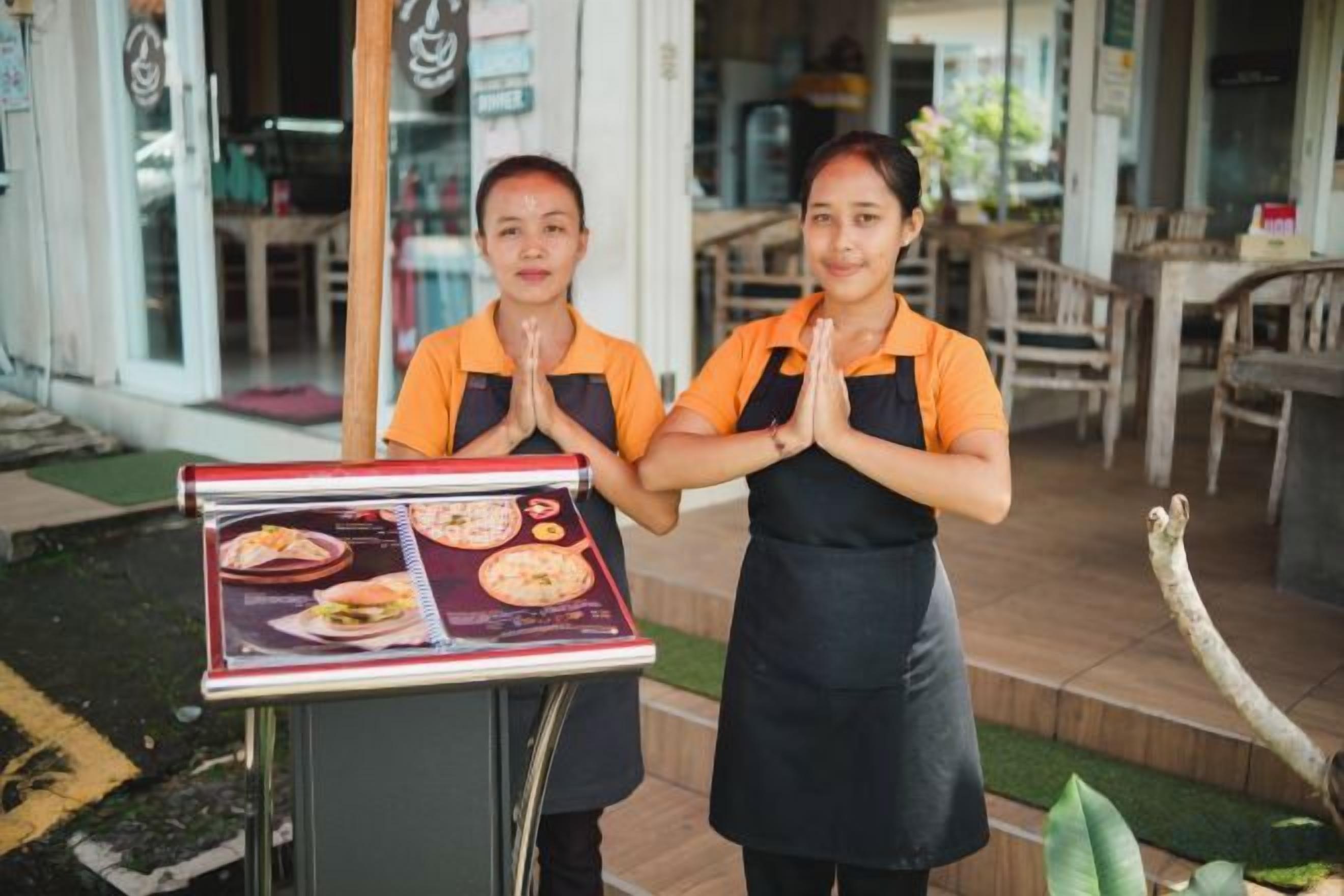 Two individuals in uniform standing in front of a food display with a menu.