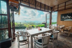 Un'area pranzo con tavolo e sedie, ampie finestre e vista sul paesaggio.