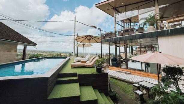 Una casa moderna con piscina, mobiliario de exterior y un amplio ventanal con vistas al paisaje.