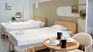 A hotel room with two beds, a round table with a coffee pot, cups, and a chair. - Imperio Melaka by Iconique (Melaka)