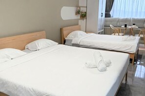 A hotel room with two beds, a small table, and a sofa.