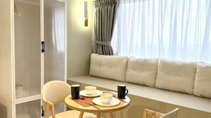 A room with a sofa, a table with cups and a plate, and a wardrobe. - Imperio Melaka by Iconique (Melaka)