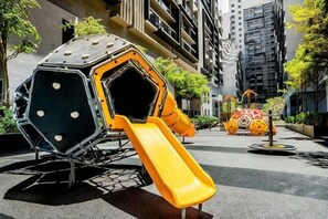 Un parque infantil con tobogán y estructura de escalada en un entorno urbano.