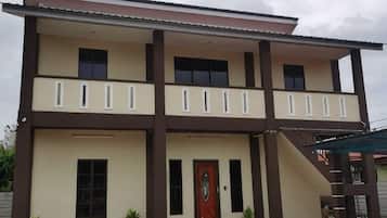 A two-story building with a balcony on the upper floor, a central entrance with a door, and a staircase leading to the upper level.