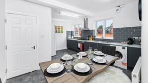 Una cocina moderna con comedor listo para seis personas. Incluye horno empotrado, lavadora y un amplio ventanal que proporciona luz natural.