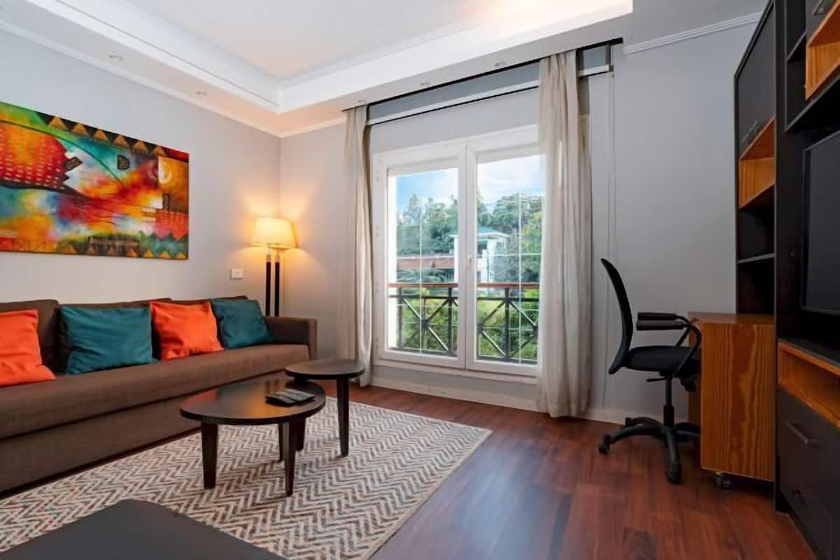 A modern living room with a sofa, coffee table, and a painting on the wall.