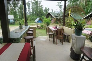 Un área de patio al aire libre con una mesa larga, varias sillas y una barra pequeña.