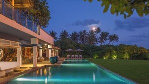 A modern poolside area with a clear view of the pool, lounge chairs, and a well-lit outdoor space. - Ravana Garden (Hambantota)
