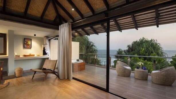 A modern room with a large sliding glass door to a balcony overlooking the sea. - Ravana Garden (Hambantota)