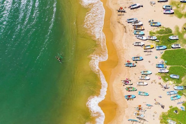 Una playa con barcos y sombrillas.