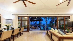 A spacious living area with a dining table and chairs, a sofa, and a television. - Aqua Vista 28: 3BR Thai Style Villa (Koh Samui)