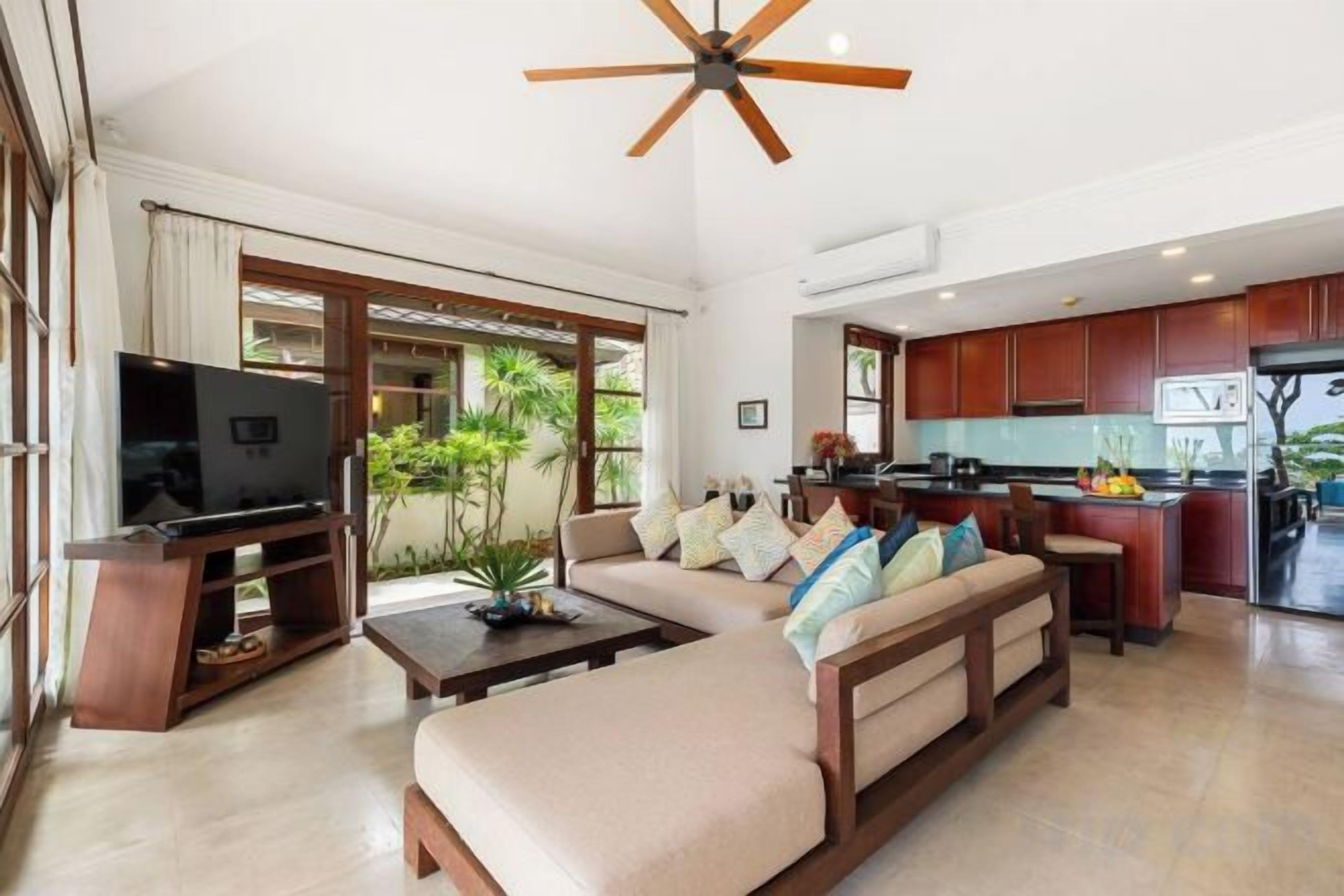 A modern living room with a sofa, television, and a ceiling fan.