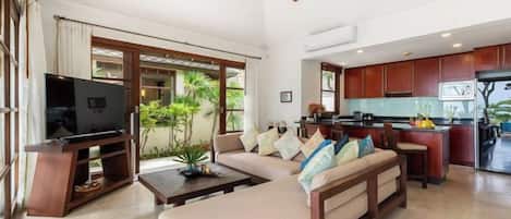 A modern living room with a sofa, television, and a ceiling fan.