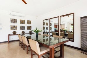 Un comedor con mesa de vidrio, sillas y decoración mural.