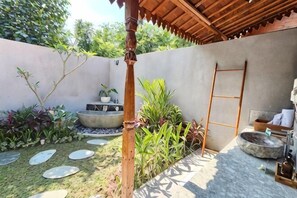 A patio with a concrete wall, a wooden ladder, a stone basin, and a small seating area. - Bhalance Retreat, Mind and Soul (Bali)