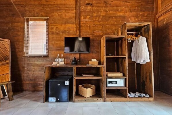 A wooden interior with a television, shelves, a wardrobe, and a small table.