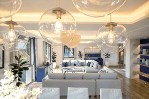 A modern living room with a sofa, coffee table, and large glass pendant lights. - Phuket Royal Marina & Resort 4 bedroom Penthouse (Phuket)