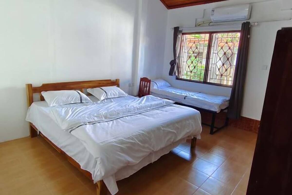 A room with a wooden bed, a small table, and a window with metal bars.