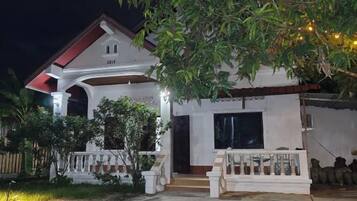 A two-story house with a porch, a garage, and a well-lit entrance.
