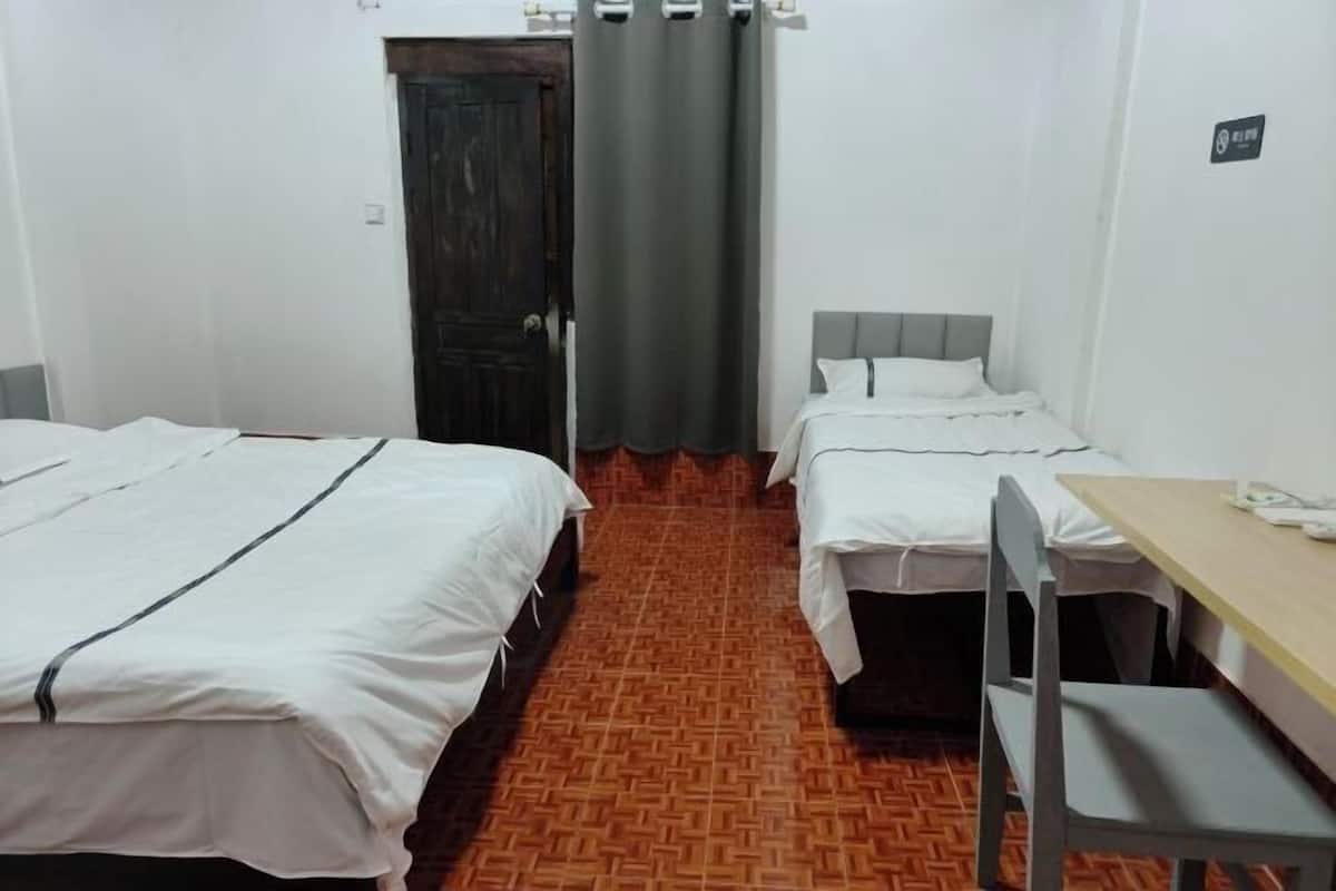 A room with two beds, a table, and a chair.