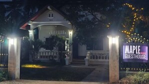 Ein Haus mit Veranda, einem Schild mit der Aufschrift 'Maple Guesthouse' und einem gut beleuchteten Eingang.