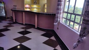 A hotel lobby with a checkered floor, a reception desk, and a window with a view of greenery. - Baaz Hotel Kakamega (Kakamega)