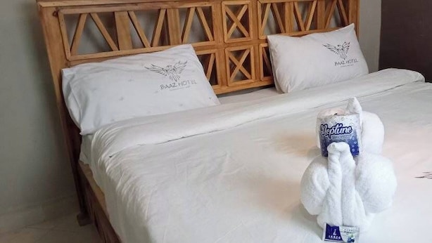 A neatly made bed with a plush white towel and a bottle of Neptuné soap. - Baaz Hotel Kakamega (Kakamega)