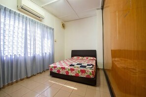A bedroom with a bed, curtains, an air conditioning unit, and a wooden panel wall. - 63 Guesthouse (Jalan Bakri)
