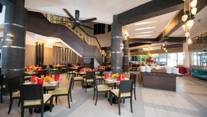 A spacious restaurant with multiple dining tables, a central staircase, and a modern ceiling fan. - 3 Bedroom Blissful Suite, Glory Beach Resort (Port Dickson)
