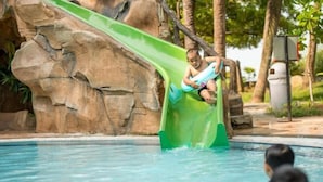 A pool with a green slide and a rock formation in the background. - 3 Bedroom Blissful Suite, Glory Beach Resort (Port Dickson)
