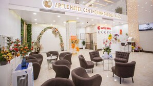 A hotel lobby with a reception desk, seating area, and a Christmas tree. - Apple Hotel (Can Tho)