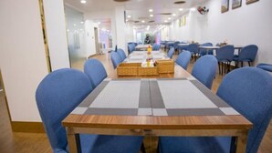 Un salón de conferencias con una mesa larga, sillas azules y una decoración central.