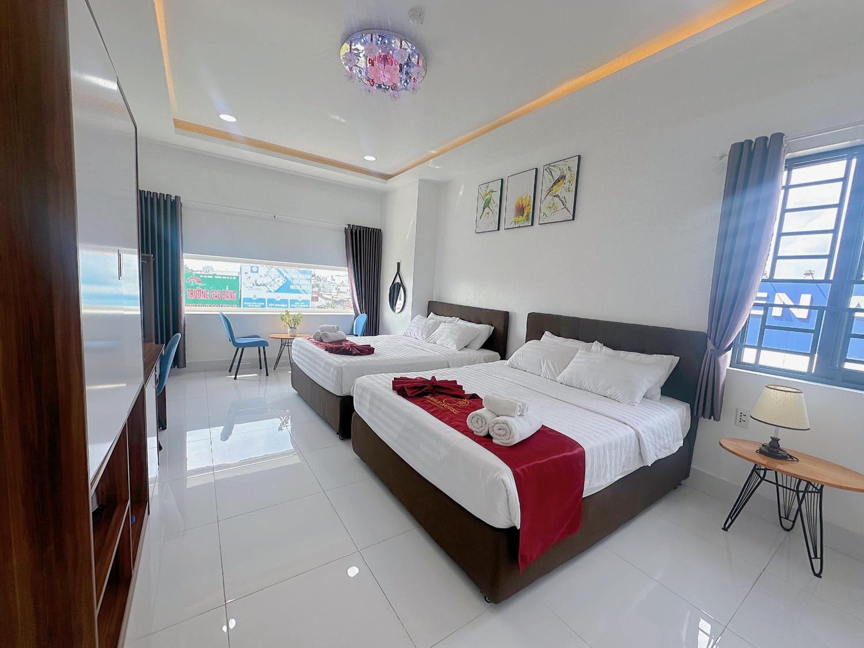 Quarto de hotel com duas camas, uma mesa de jantar, um espaço de estar pequeno e vista para a cidade.