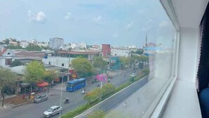 Vista desde una ventana sobre una calle con edificios, un autobús y vehículos.