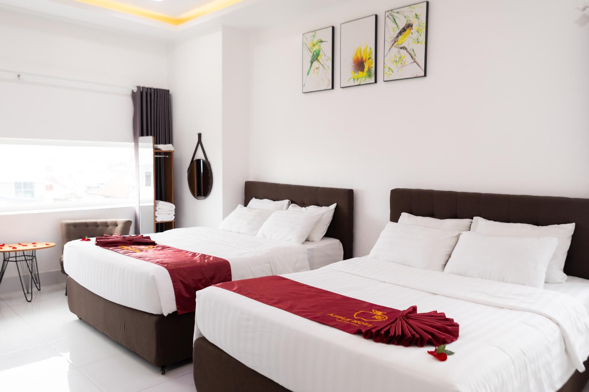 Une chambre d’hôtel avec deux lits, une petite table et des œuvres d’art accrochées au mur.