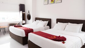 A hotel room with two beds, a small table, and artwork on the wall. - Apple Hotel (Can Tho)