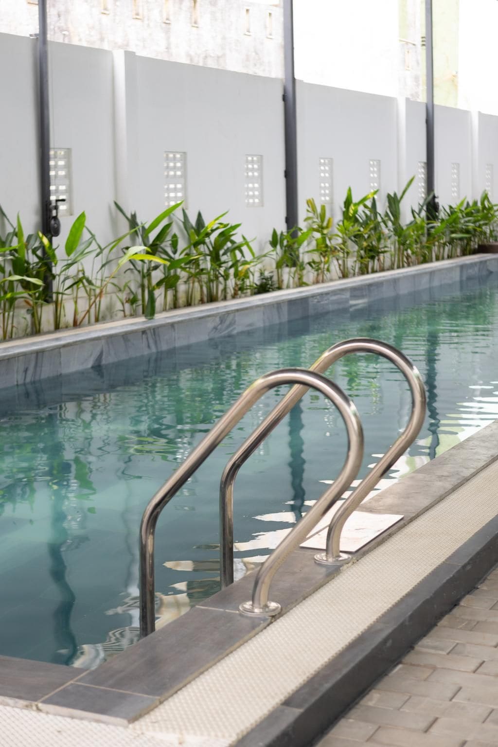 Una piscina con barandillas metálicas y un borde con azulejos.