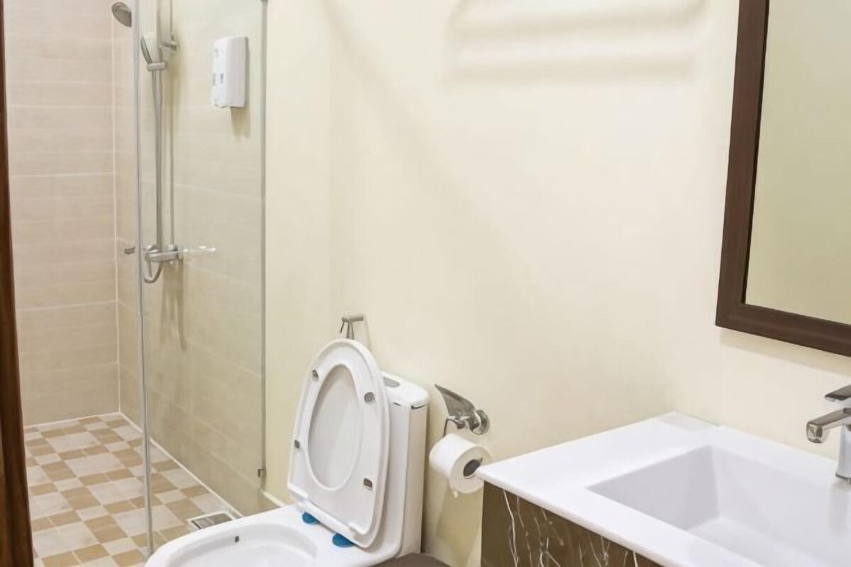 A bathroom with a shower, toilet, sink, and mirror.