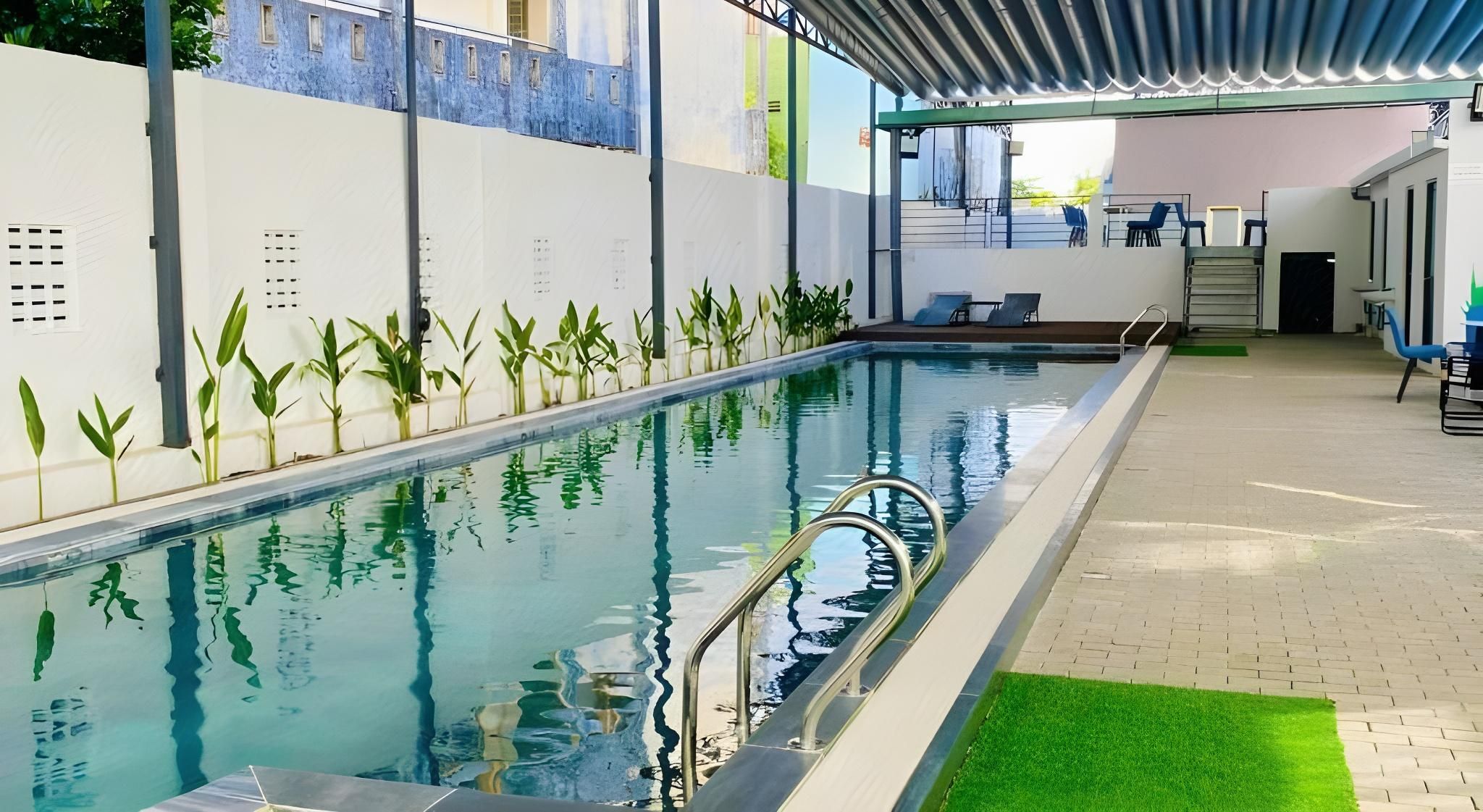 An indoor swimming pool with a clear water surface, surrounded by a tiled floor and a green artificial turf area.