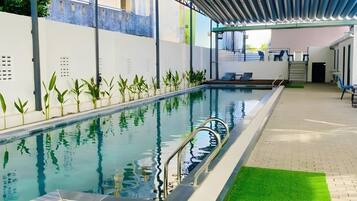 An indoor swimming pool with a clear water surface, surrounded by a tiled floor and a green artificial turf area.