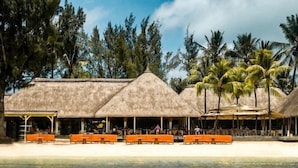 Un resort frente al mar con estructuras de techo de paja y bancos de madera.