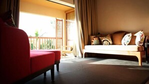 Una habitación con un sofá rojo, un banco de madera y una cama con almohadones estampados.