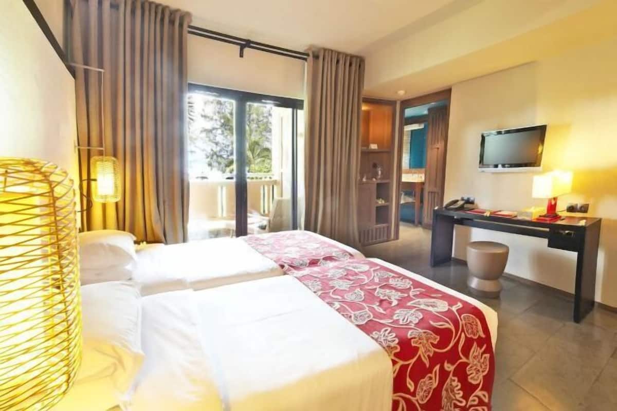 Habitación de hotel con dos camas, un escritorio, un televisor y un balcón.
