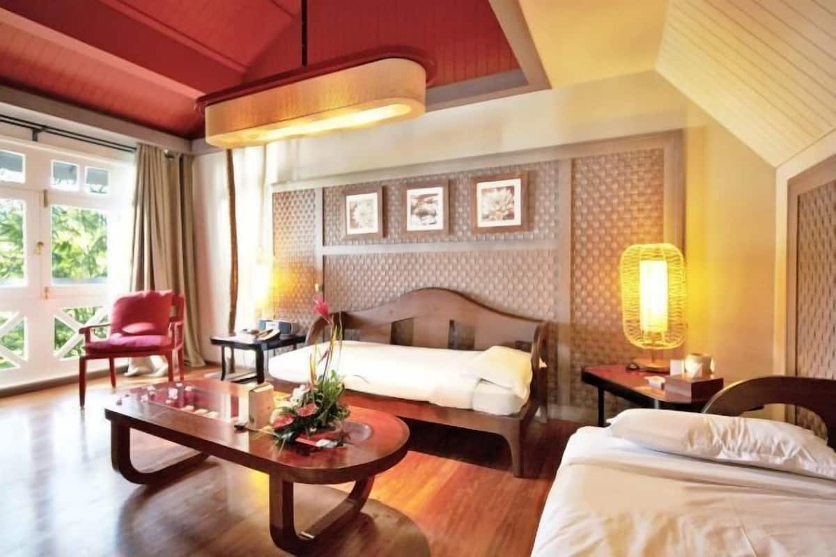Habitación de hotel con cama, escritorio, silla, una mesa con flores y vistas por la ventana.