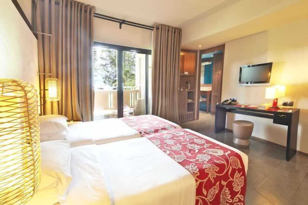 Una habitación de hotel con dos camas, un escritorio, un televisor y vistas al exterior.
