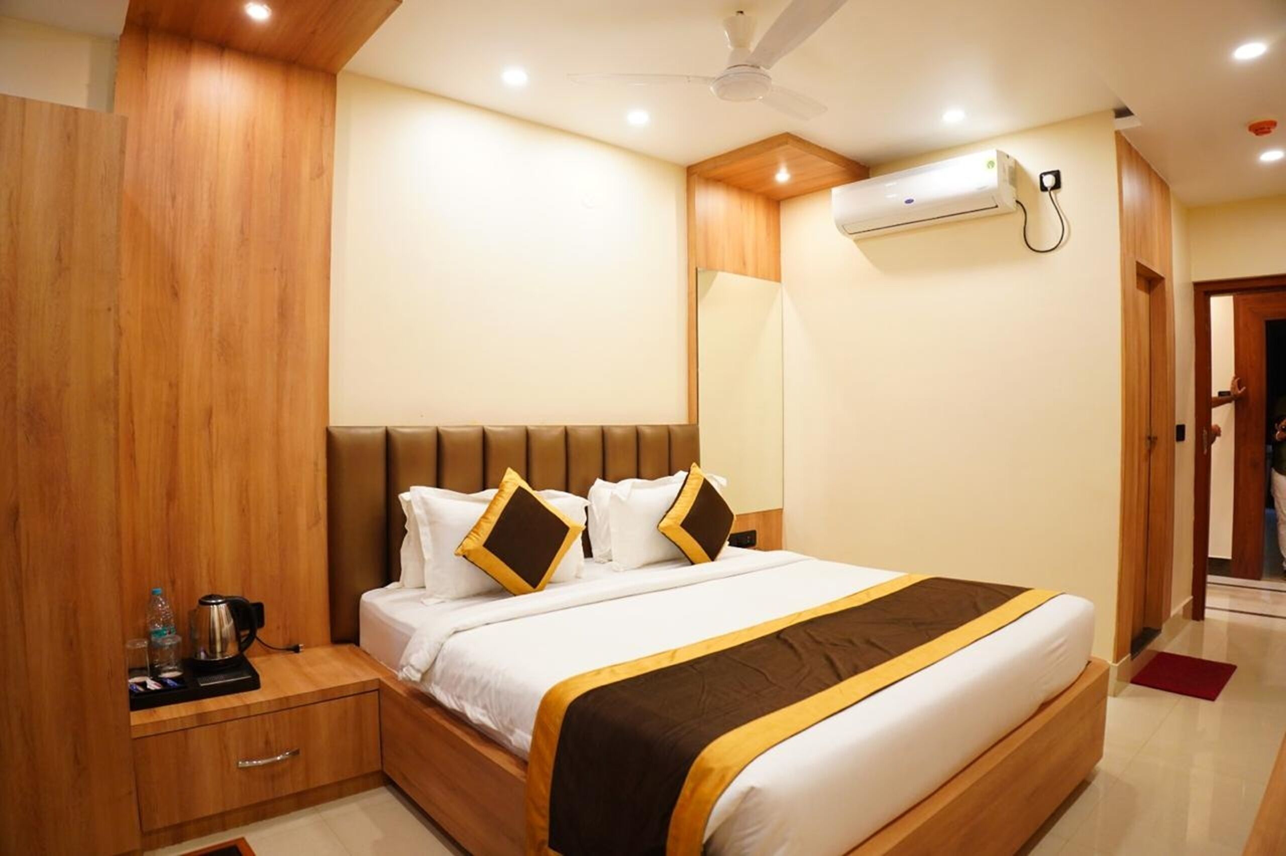 Een hotelkamer met een groot bed, een houten hoofdeinde en een airconditioning aan de muur.