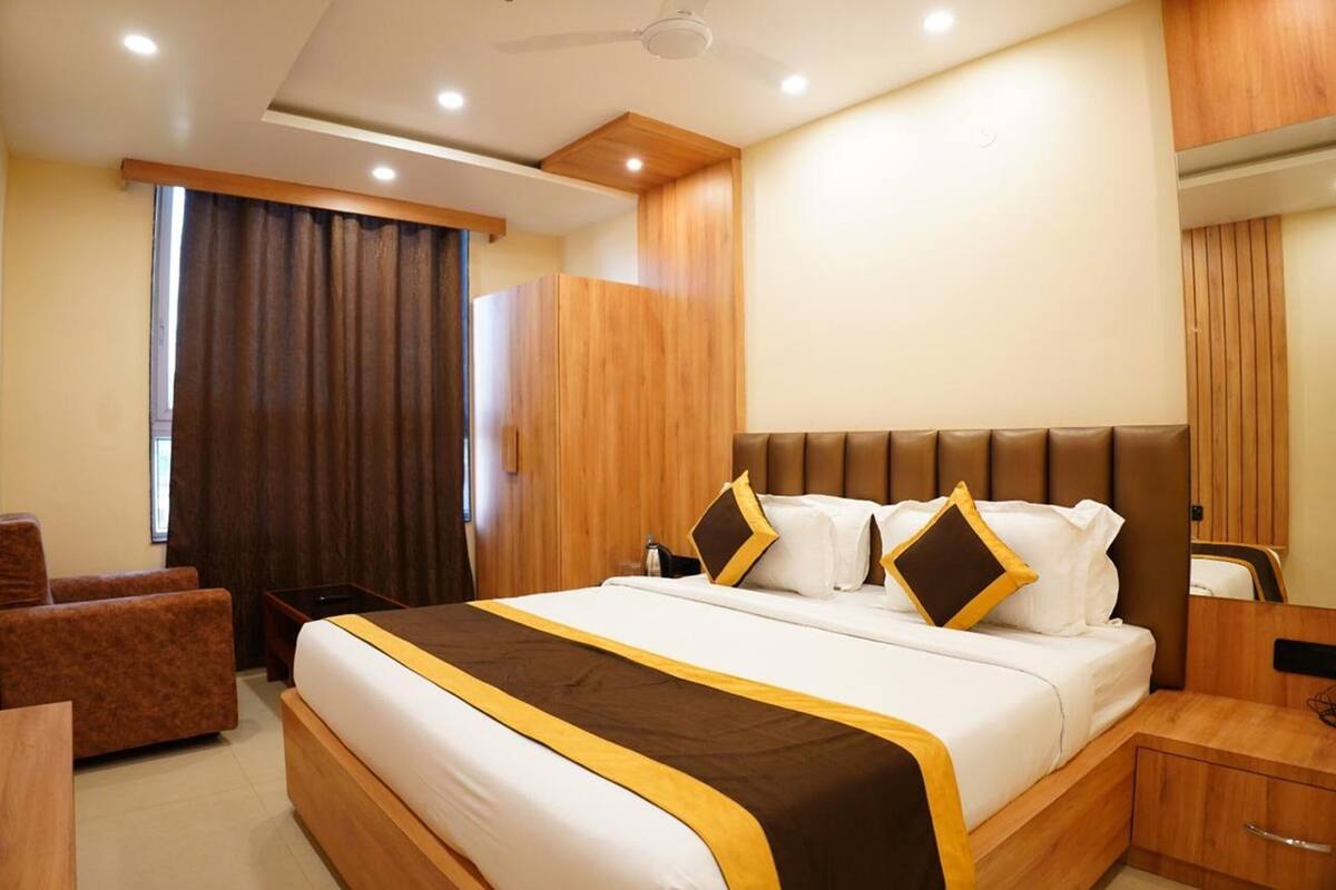 A hotel room with a large bed, a wooden headboard, a desk, and a chair.